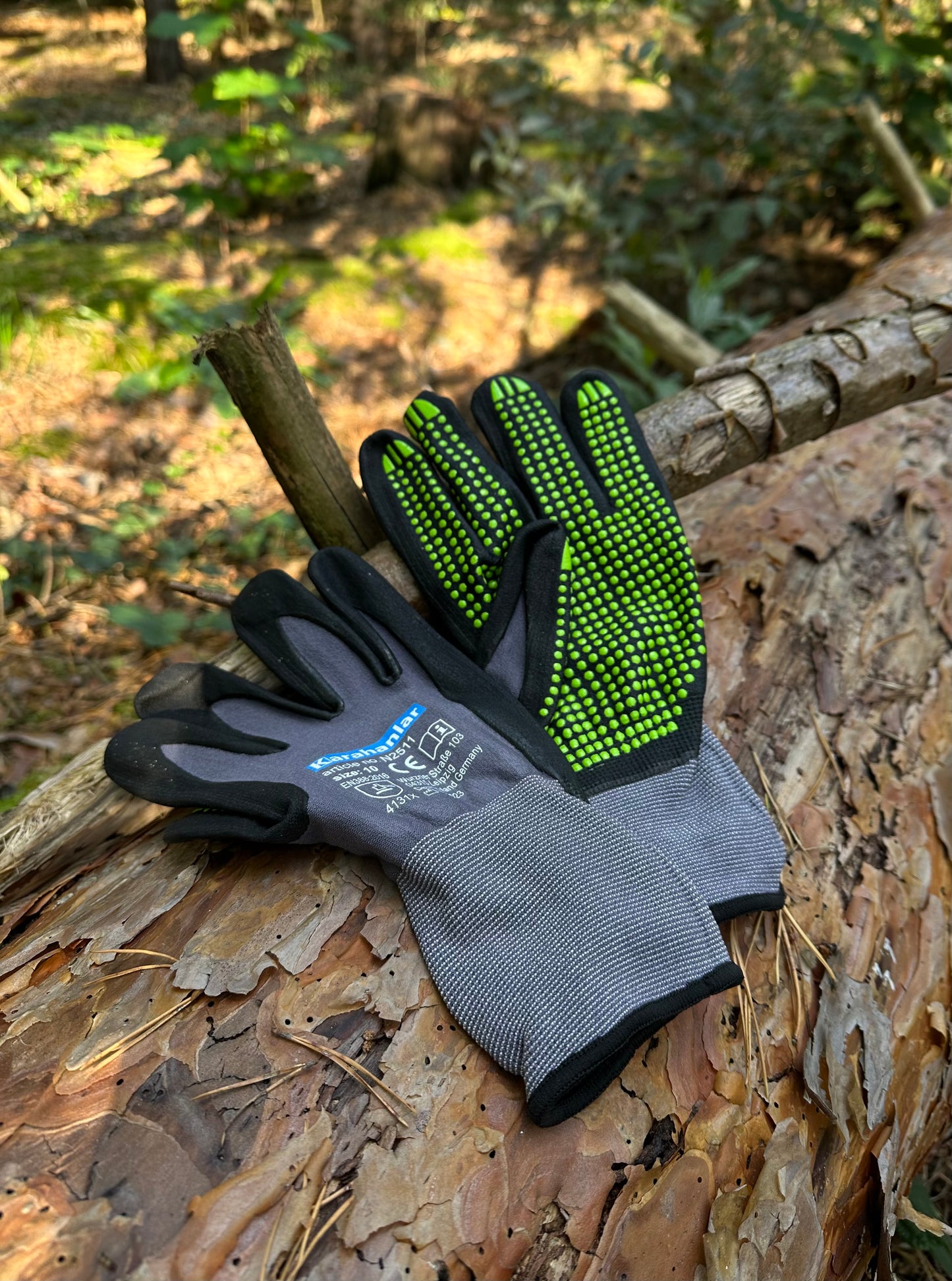 Super flexible Handschuhe in schwarz/grauer Farbe mit grünen Noppen im Wald