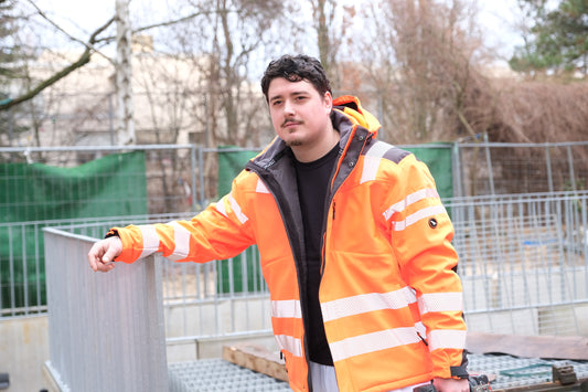 Ein Mann mit warnoranger Arbeitsjacke mit Reflektoren